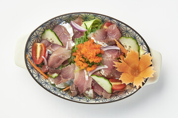 Beautifully presented sashimi salad featuring fresh slices of raw fish, vibrant vegetables, and garnish of fish roe, served in decorative bowl. dish is colorful and appetizing
