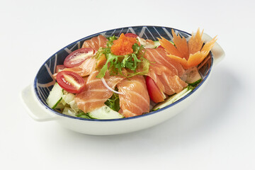 Bowl of fresh salmon sashimi salad with vibrant vegetables, garnished with fish roe and decorative carrot flower, served in patterned ceramic dish