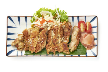 Crispy fried chicken slices served on rectangular plate with fresh lettuce, cherry tomatoes,...