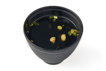 Black bowl filled with dark soy based dipping sauce garnished with chopped green onions, commonly used for cold noodle dishes or as flavorful condiment