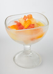 Glass dessert bowl filled with colorful diced fruits, including watermelon, pineapple, and papaya, served on white background. vibrant colors create refreshing and appetizing presentation