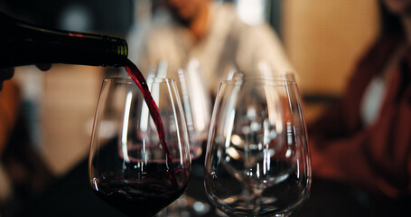 Bartender, glasses and wine with bottle for fine dining, alcohol or hospitality in restaurant. Closeup, group or liquid brew with friends, get together or social event for drink, toast or celebration