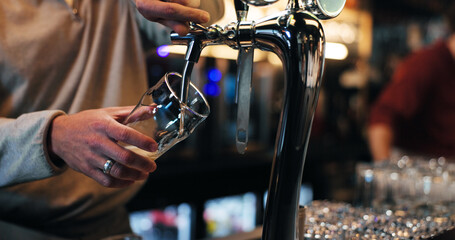 Bartender, hands and glass with dispenser for draft, customer service or pouring drink in bar. Closeup, barman or preparing beverage with tap for alcohol, hospitality or order in restaurant or pub