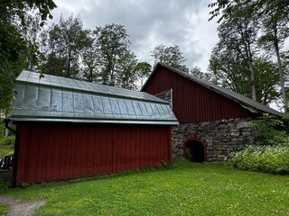 Fagervik, Finland: Two red barns with stone foundations and metal roofs in Finnish countryside,...