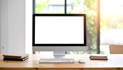 Fototapeta premium Bright workspace featuring a desktop computer with blank screen, keyboard, mouse, and notebooks