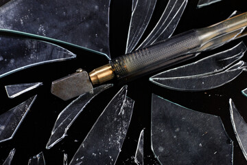 A glass cutter lying on a broken glass