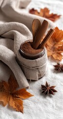 Autumnal spice blend in a jar, draped in linen cloth, with fallen leaves and wooden utensils