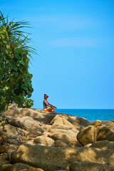 a woman meditates on the rocks by the sea