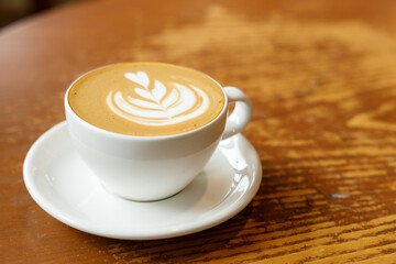 Cup of hot milk latte coffee on table by the window.