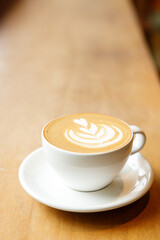 Cup of hot milk latte coffee on table by the window.