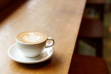 Cup of hot milk latte coffee on table by the window.
