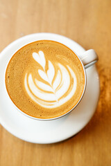 Cup of hot milk latte coffee on table by the window.