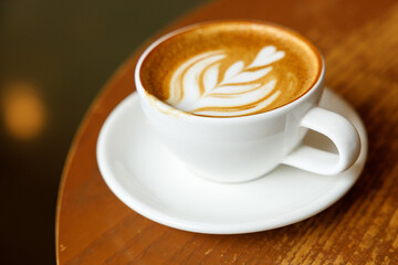 Cup of hot milk latte coffee on table by the window.
