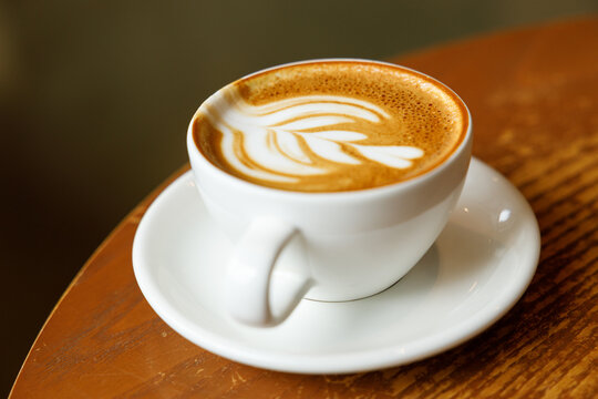 Cup of hot milk latte coffee on table by the window.