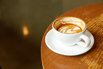 Cup of hot milk latte coffee on table by the window.