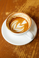 Cup of hot milk latte coffee on table by the window.