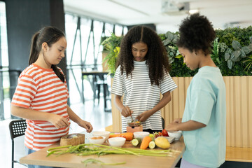 group of multi-ethnic children girls are learning how to cooking with miniature kitchen utensils,...