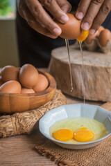 A person is cracking an egg into a white bowl.