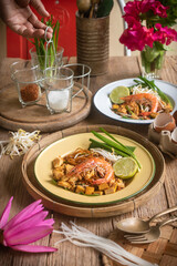 Pad Thai with rice vermicelli and shrimp with ingredients placed on the table.