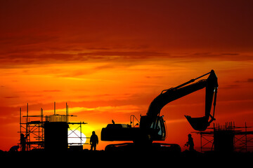 Construction site silhouettes against a vibrant orange sunset sky