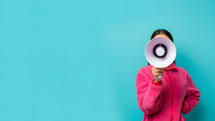 A woman holding a megaphone in front of her face on a blue background