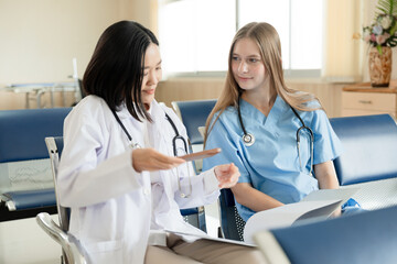 Caucasian doctor woman working and talking with major Asia woman medical student at hospital	
