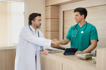 Major Caucasian man doctor hand shake with medical student use tablet computer working at hospital	