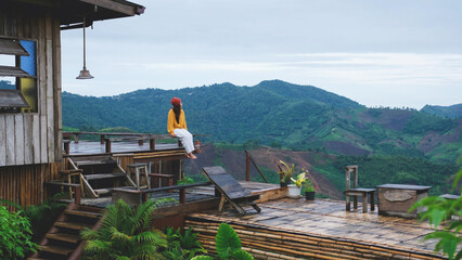 A woman sitting on wooden terrace and looking at a mountain view