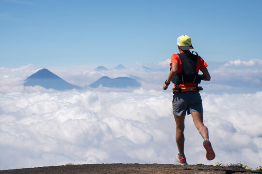 One man running at a high altitud mountain towards a sea of clouds