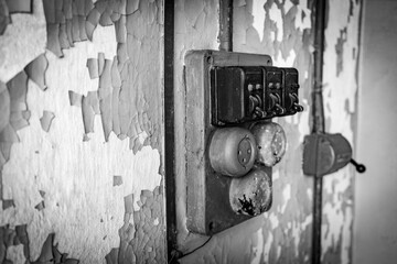Old Electrical Switches and Peeling Paint on a Wall - monochrome