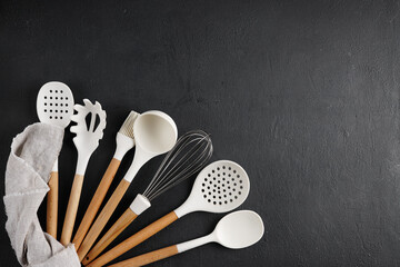 A set of kitchen utensils with a wooden handle on a black background. isolated object. top view, copy space on the right