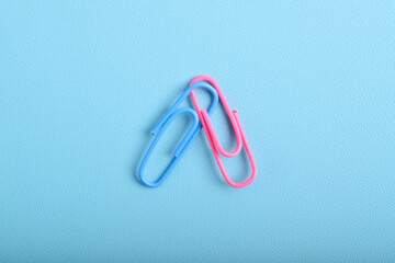 Two paper clips isolated on light blue background