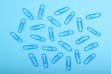 Many blue paper clips isolated on light blue background, flat lay