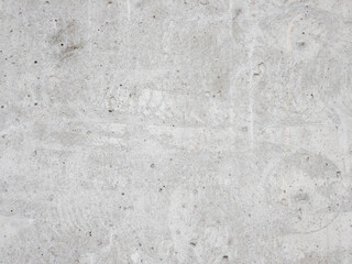 A grey concrete wall with a lot of holes and cracks. The wall is very rough and uneven