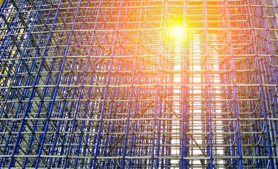 Construction scaffolding stands tall against a bright sunset in an urban setting