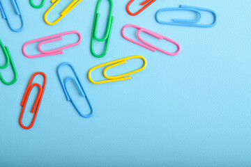 Colorful paper clips isolated on light blue background. Copy space. Copy space for your text and information