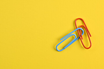 Two paper clips isolated on yellow background