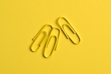 Three blue paper clips isolated on yellow background