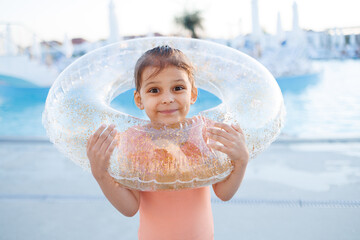 Cute funny toddler girl relaxing on inflatable toy ring floating in pool have fun during summer...