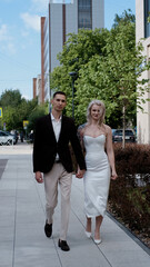 A bride and groom in love walking along a city street in summer