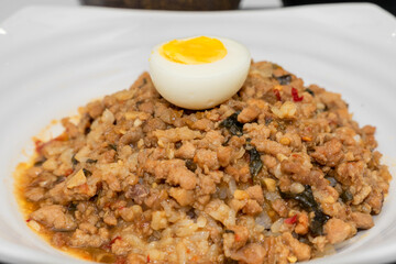 A Thai basil minced pork set meal arranged on a tray, including a portion of stir-fried spicy basil pork, a bowl of steamed white rice, three side vegetables, and a bowl of soup. The presentation refl
