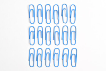 Many blue paper clips isolated on white background, flat lay