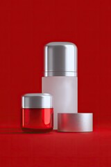 Three cosmetic containers,  red and silver, on a red background
