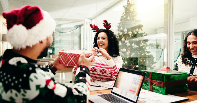 Christmas, gift and heart hands with business people in office together for celebration or party. Present, smile and thank you with employee team in workplace for festive surprise or tradition - Powered by Adobe