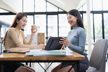 Two young Asian businesswoman and looking at digital tablet company device in office. 