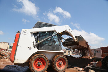 skid steer loader working construction site. mini loader transports excavation waste at...