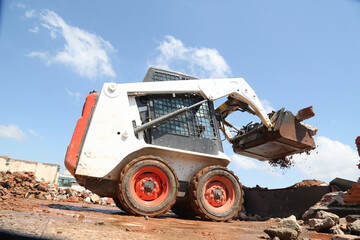 skid steer loader working construction site. mini loader transports excavation waste at...