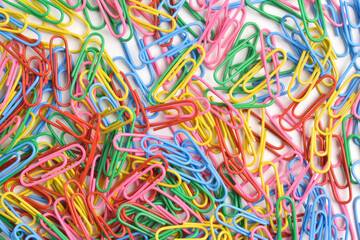 Pile of colorful paper clips on white background, top view
