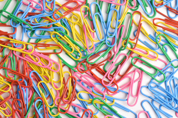 Pile of colorful paper clips on white background, top view