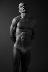 Fototapeta premium Strong man posing in a black and white image, showcasing impressive physique and confident expression. A striking portrayal of strength and masculinity in monochrome.
